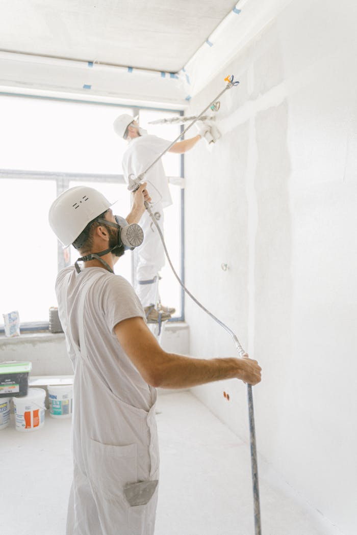 footer-02 Two professional painters working indoors on wall renovation and painting project.