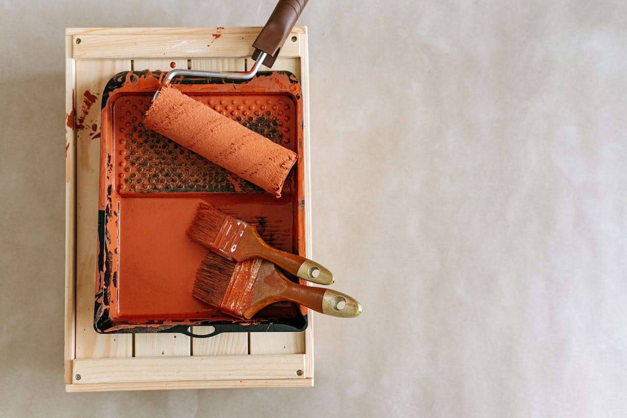 services-01 An overhead shot of paintbrushes and a roller in a tray, perfect for home renovation projects.