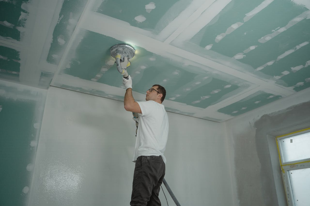 mission-img A worker expertly polishes a ceiling indoors, demonstrating home renovation skills.