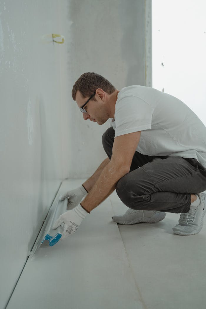 who-we-are-img A man wearing casual attire working on a home renovation project indoors with painting tools.
